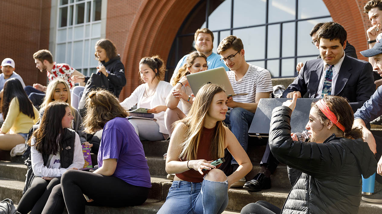A collective group of students sit on the steps on the University of Portland campus