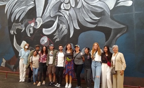 A group of students and faculty on the Quito faculty-led program pose in front a mural