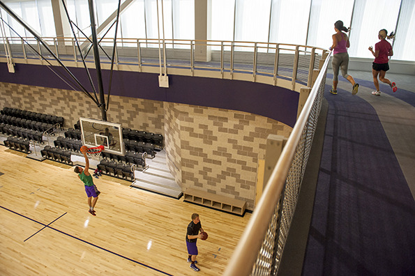 Two students playing basketball and two student running on the suspended track in the Beauchamp Recreation and Wellness Center