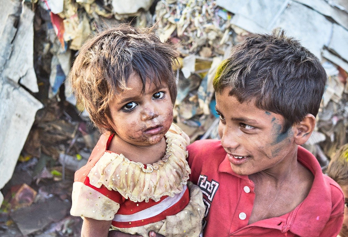 Boy and girl with dirty faces in front of a pile of garbage