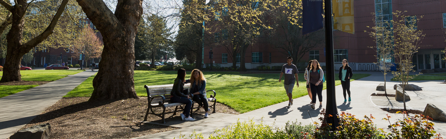 Students walk under trees outside of Swindell's Hall.