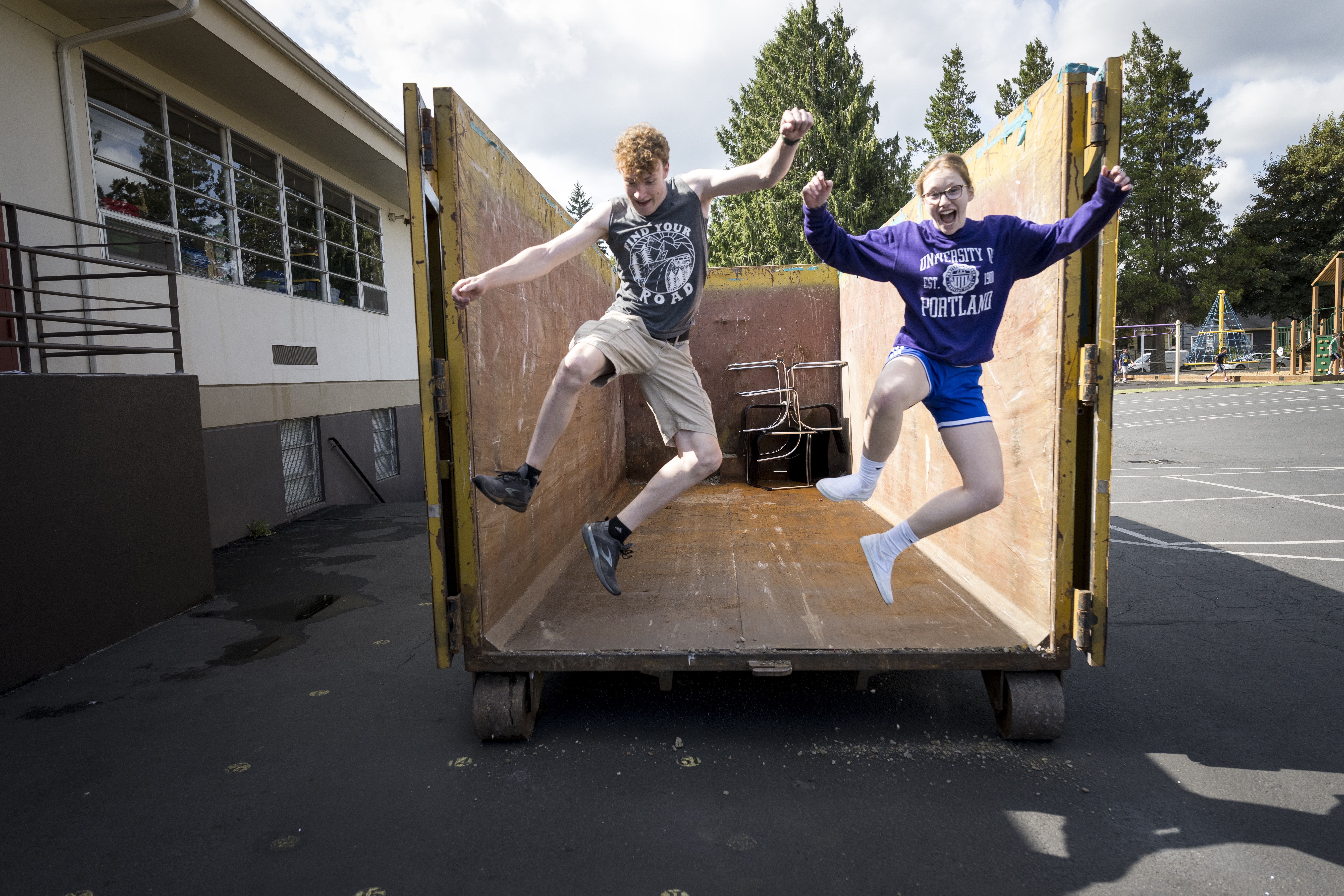 Two students on 2023 Plunge jumping out of a trailer with their feet in the air and smiling.