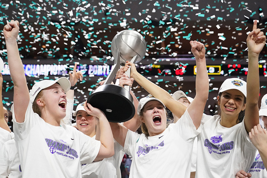 Women's basketball team holds trophy overhead as confetti rains down