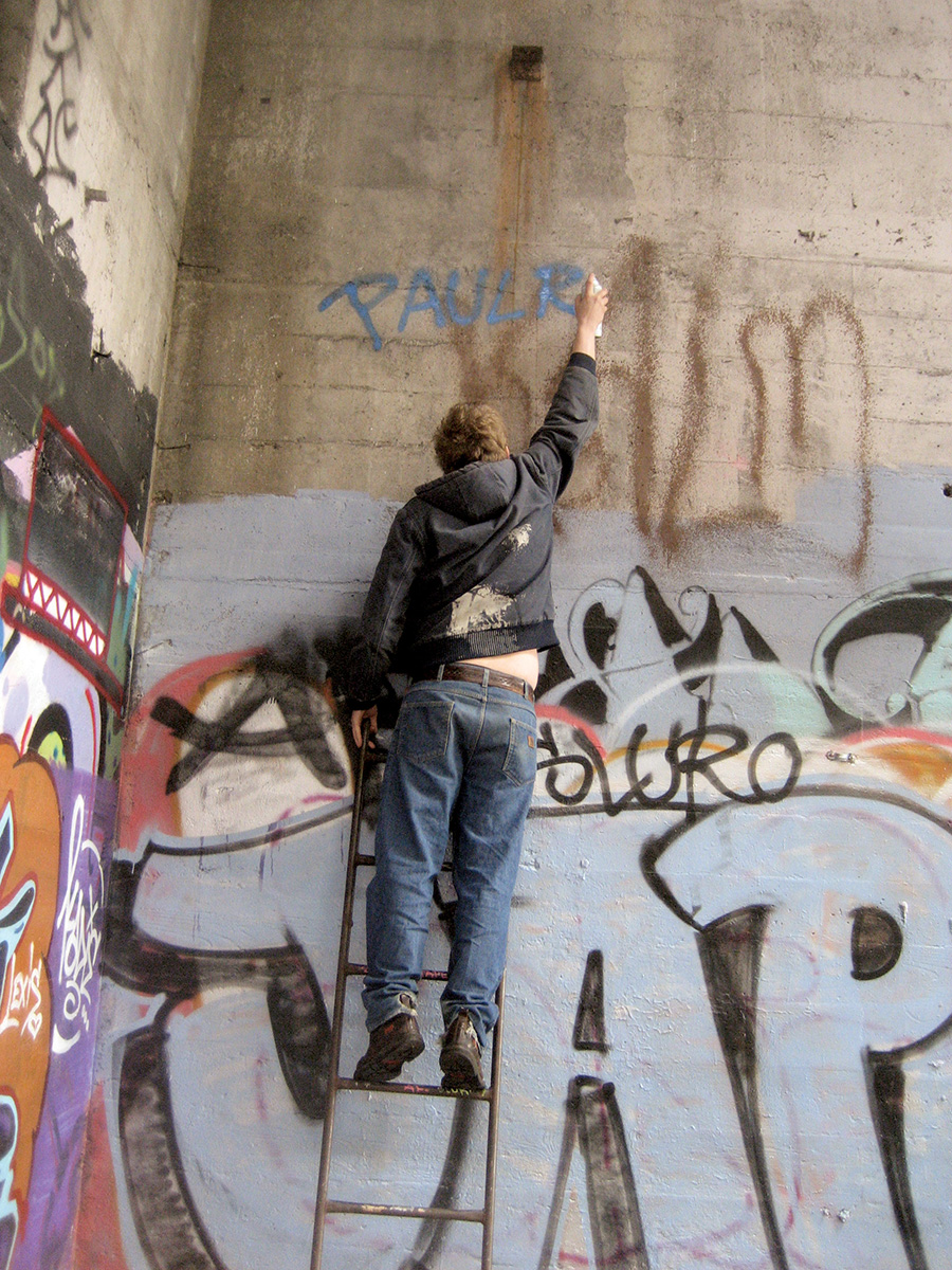 Man on ladder working on graffiti