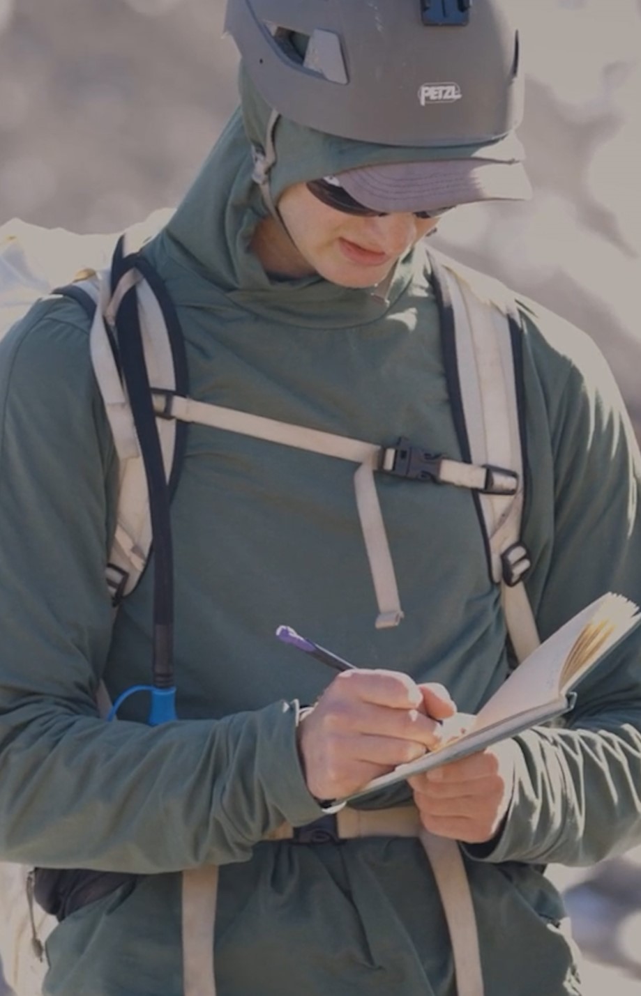 UP student Aidan, dressed in mountaineering gear, takes notes in a field notebook during research on Mt. Hood glacier.