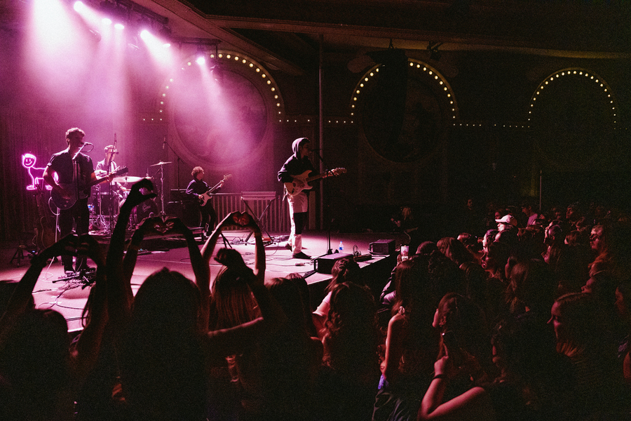 A band performs on stage, framed by purple lights, at University of Portland's Rock the Bluff campus concert.