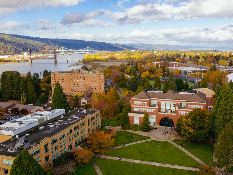 An aerial view of University of Portland's campus during fall, with St. Johns Bridge in the background.