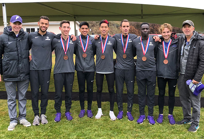 Men's cross country team standing outside with medals