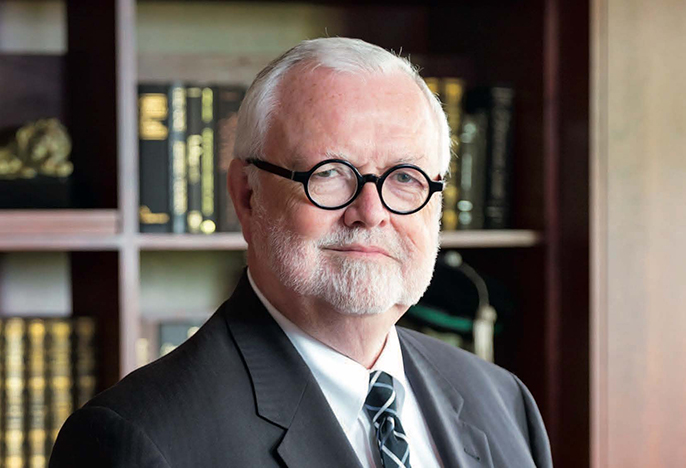 Provost Tom Greene standing in front of bookcase