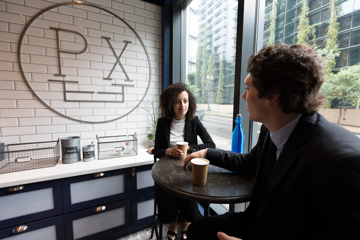 A student in professional attire sits with an interviewer at a Portland coffee shop
