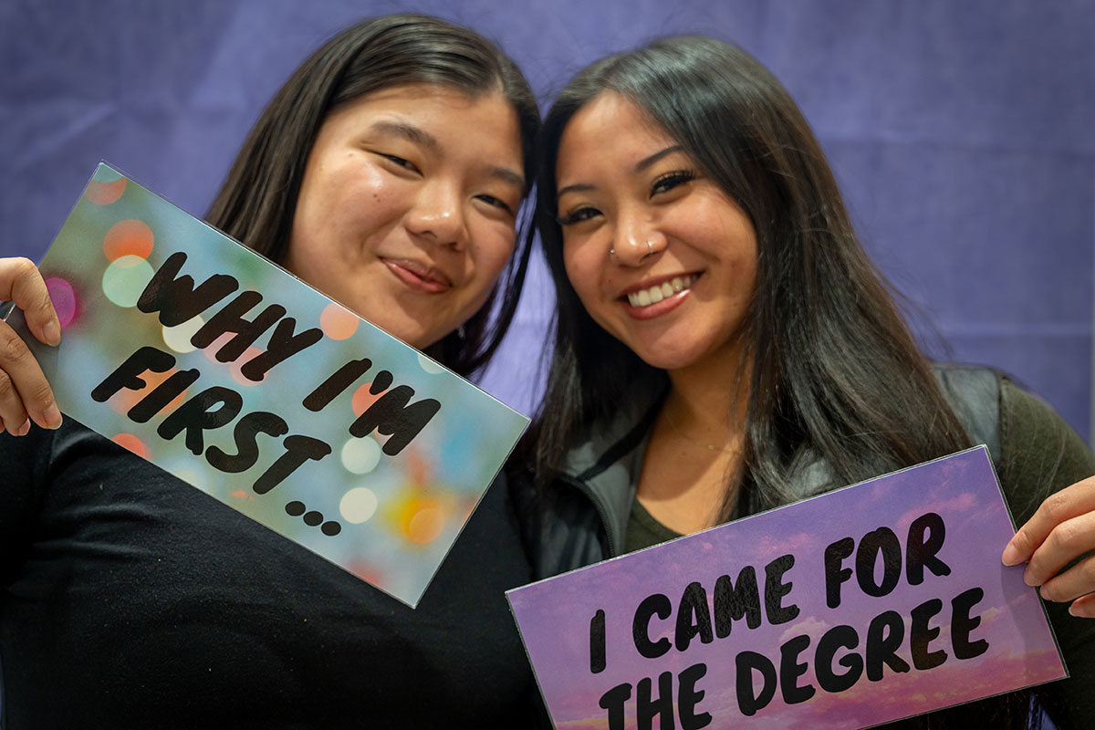 two fgen students pose with small signs that say why i am first and i came for the degree.