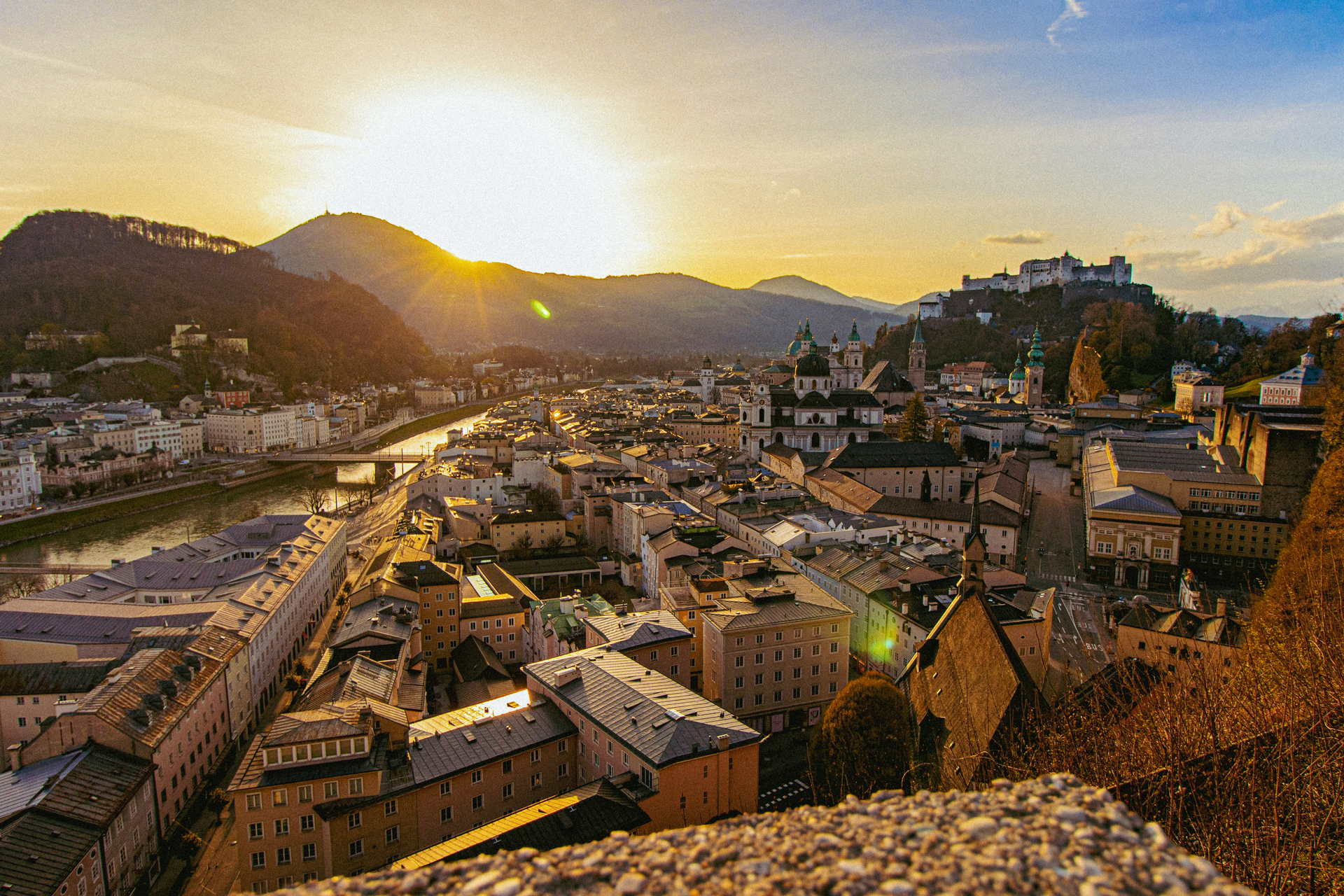 An aerial view of mountains and historic buildings in Salzburg, Austria at sunrise.