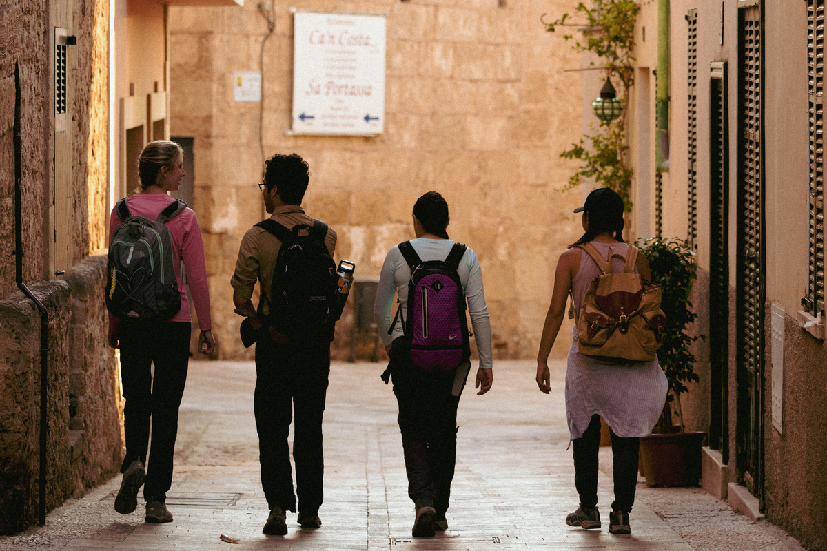 A behind view of UP students walking through a historic stone-paved alleyway in Mallorca, Spain during a study abroad trip.