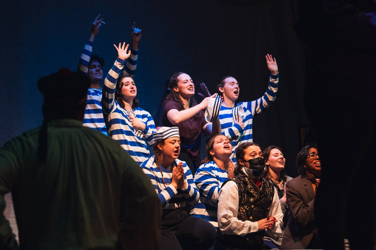 A photo of actors on a stage dressed in matching blue and white shirts