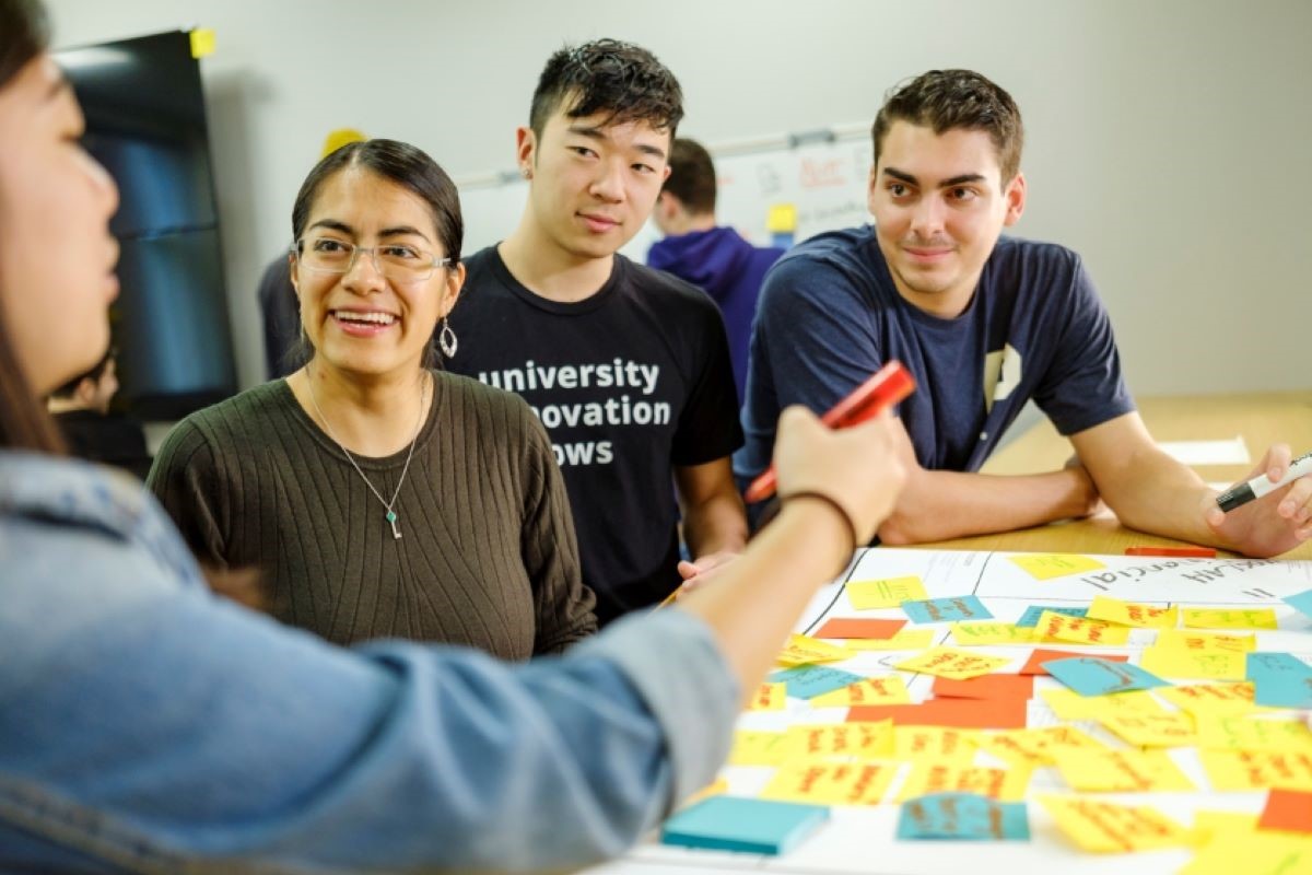 A faculty member engages with students in the innovation lab classroom.