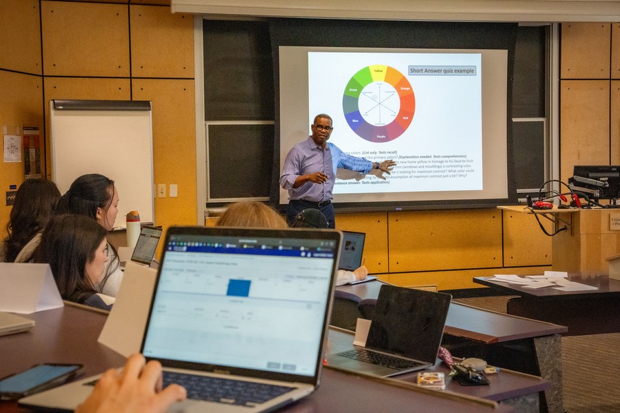 A professor points to a chart on projector screen during a business course in a classroom at UP