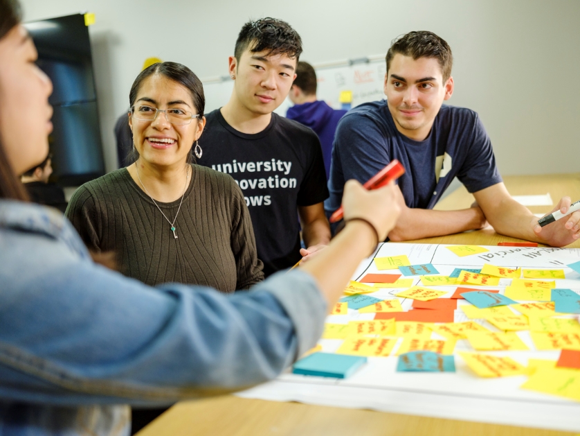 A faculty member engages with students in the innovation lab classroom.