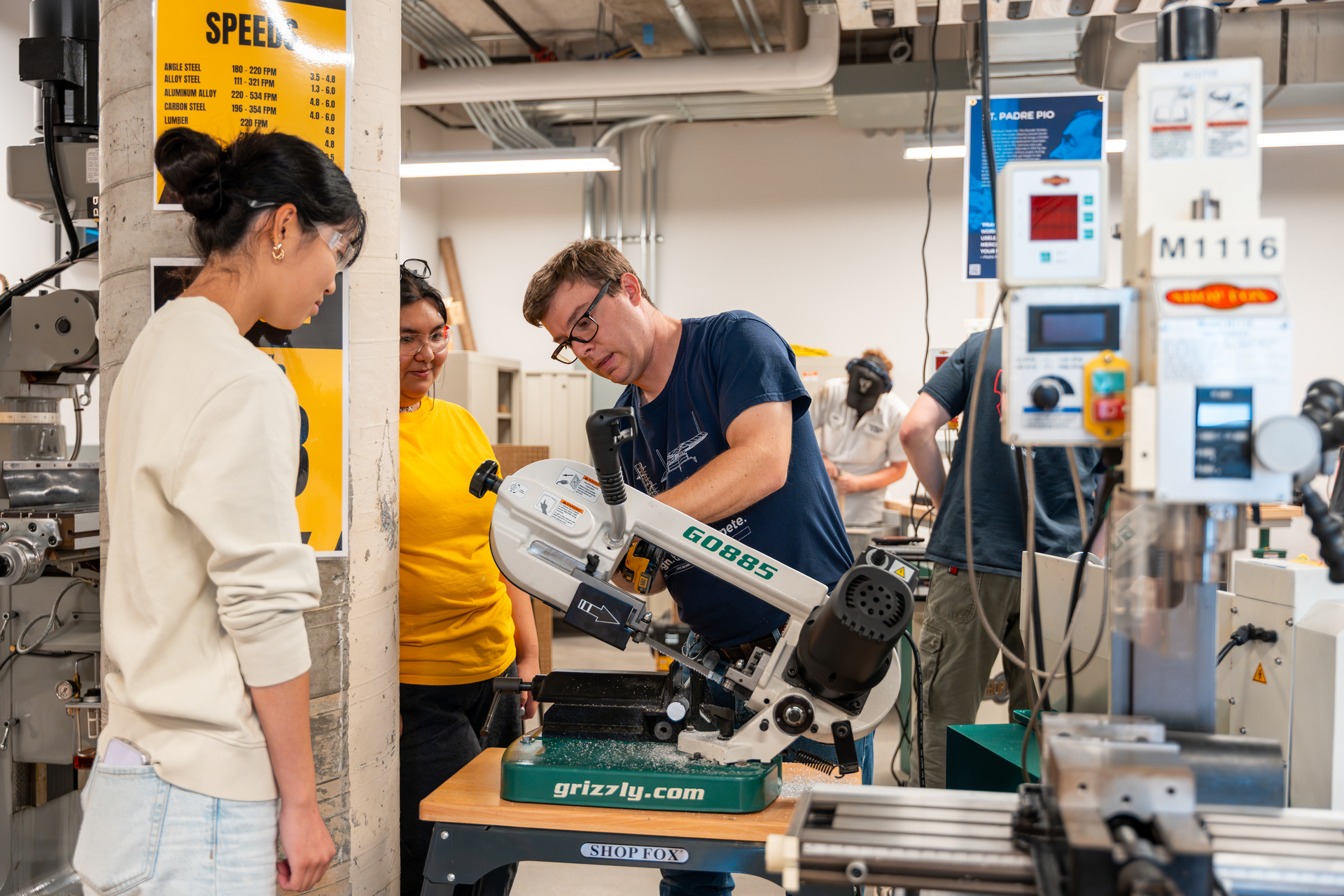 Students work with a professor in the machine lab of the SMCDI