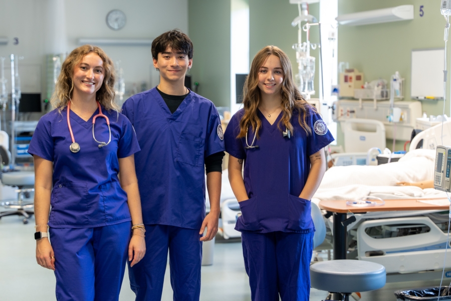 UIP nursing students in scrubs pose in the sim lab.