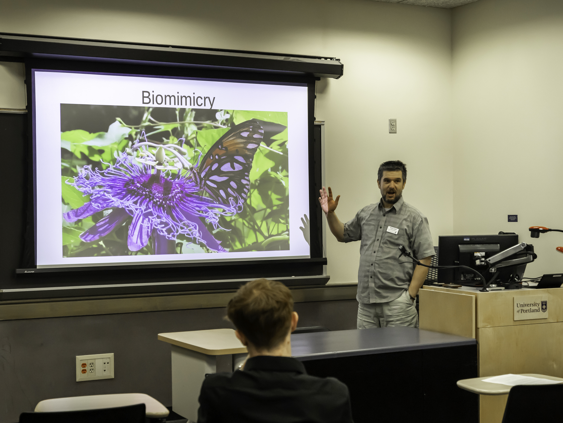 A UP professor discusses biomimicry while displaying an ai generated image on a projector screen in the classroom during a lecture.