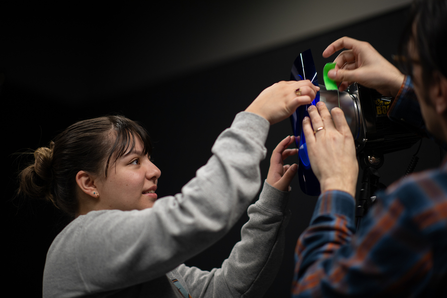An arts administration student works with faculty in the Shiley Marcos Center Digital Lab to setup lighting and camera equipment for a photo shoot.