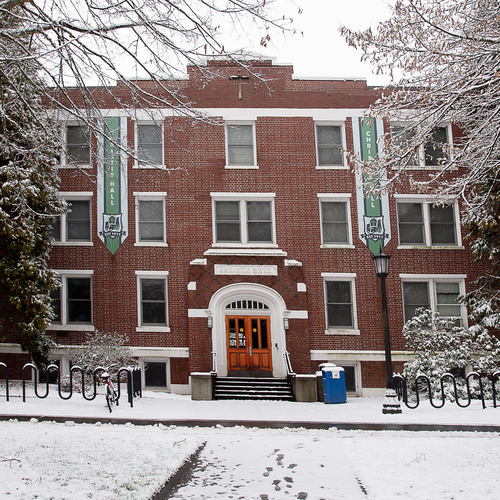 An image of Christie Hall, a residence hall and historic brick building, blanketed with white snow on a winter day.