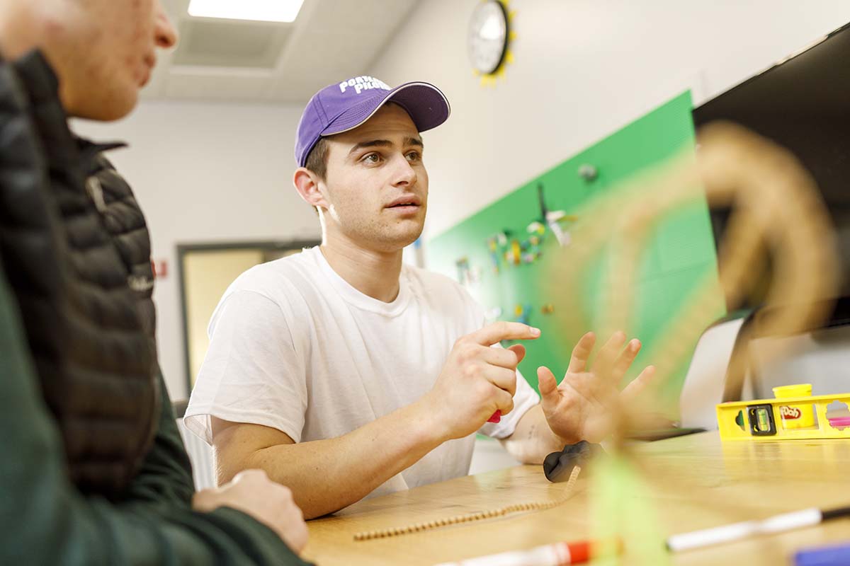 A group of business students sit at a table in the Innovation Lab at University of Portland and brainstorm product ideas using craft supplies to build models
