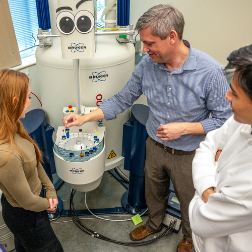 Biology students and their professor insert samples into a nuclear magnetic resonance spectroscopy machine in a laboratory at the University of Portland.