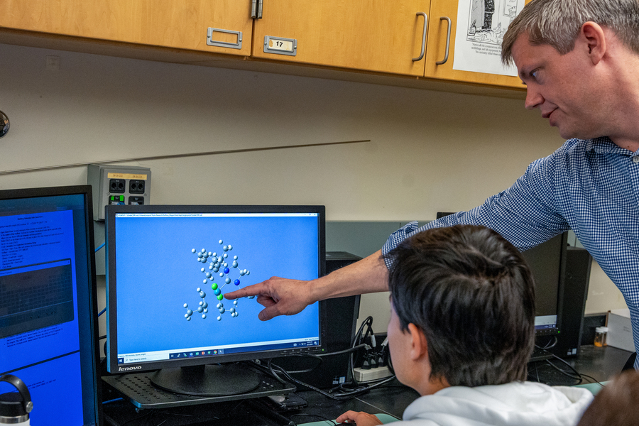 A professor providing instruction to a UP biology student points to a digital rendering of a molecular model on the computer screen of their workstation.