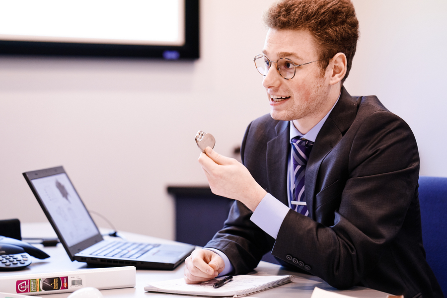 A UP chemistry student dressed in business attire seated a desk with a laptop in an office setting during an internship with Biotronik.