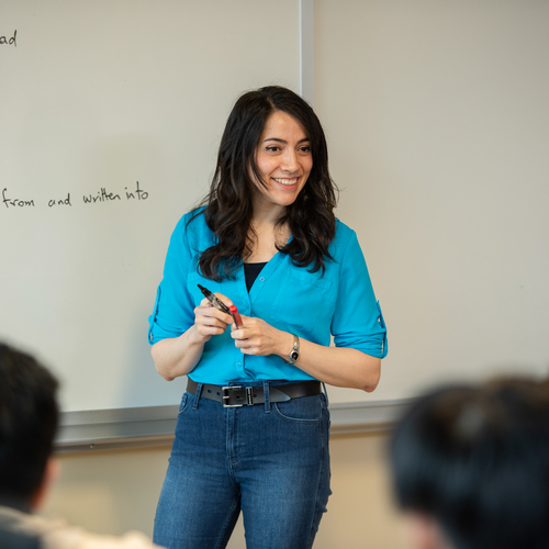 A UP engineering professor smiles as they pause in front of a classroom white board during a lecture.