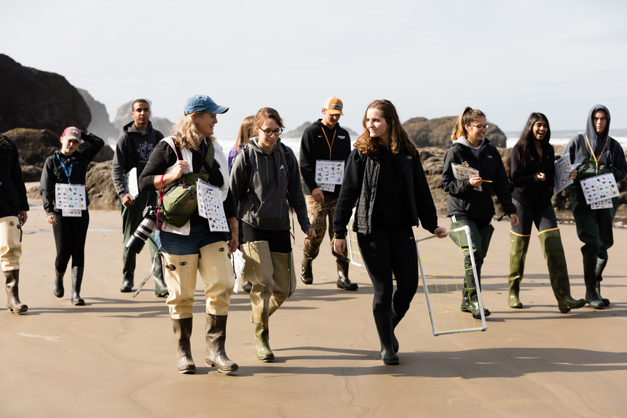 A group of University of Portland ecology students walk along the ocean shoreline in Oregon with their professor as they prepare to gather samples for research studies.
