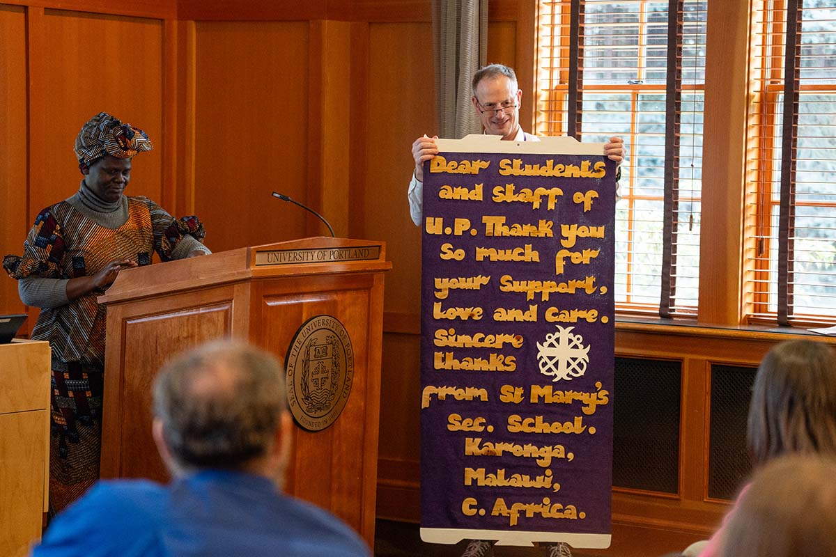 Martha Chizumila Nyondo, Principal of St. Mary’s Secondary School in Karonga, Malawi, presents a banner of thanks from her school to the University of Portland