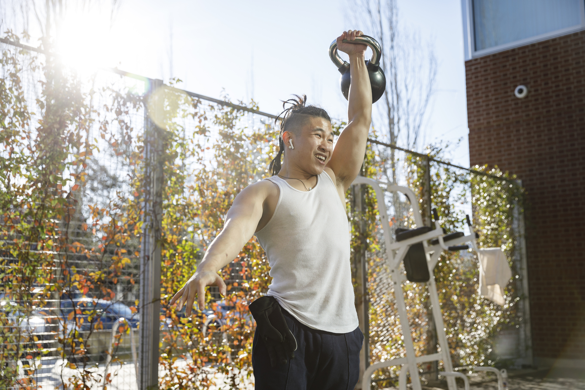 A UP student lifts a weight above their head while exercising in an outdoor space at the Beauchamp recreation center.
