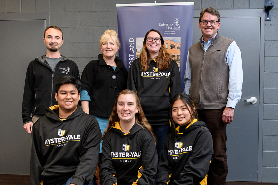A group of UP engineering students participating in an internship with Hyster-Yale pose for a picture with their professor in a university building.