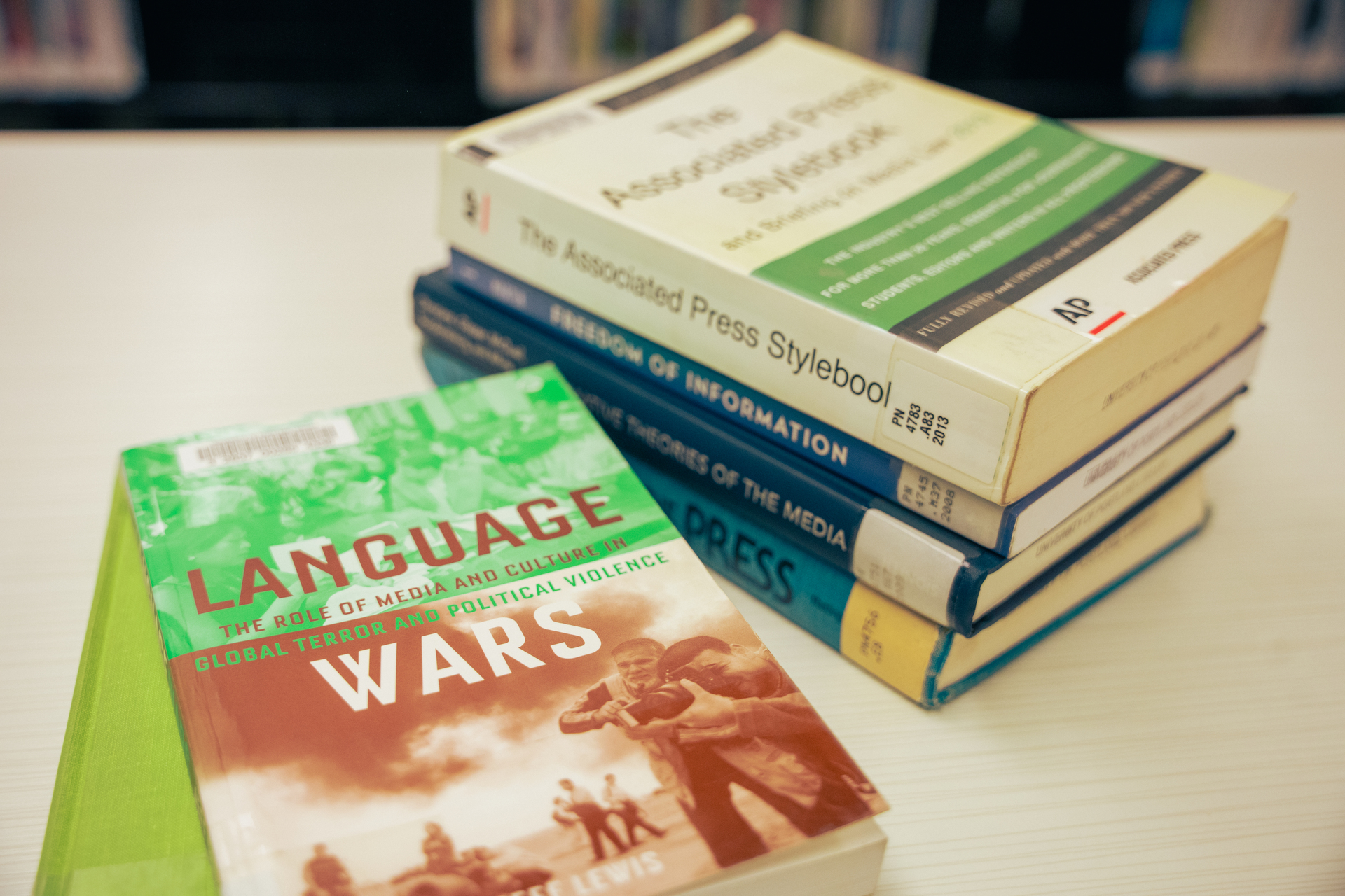 Two small stacks of media and journalism books on a table in the Clark Library at the University of Portland.