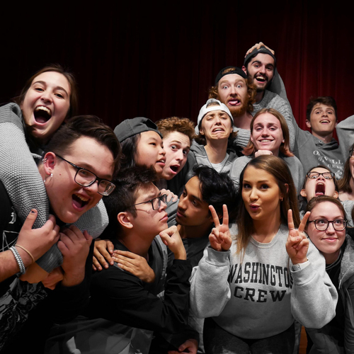 The Bluffoons, the student improv group at the University of Portland, gathers into a close clustered group while making faces and poses for the camera.