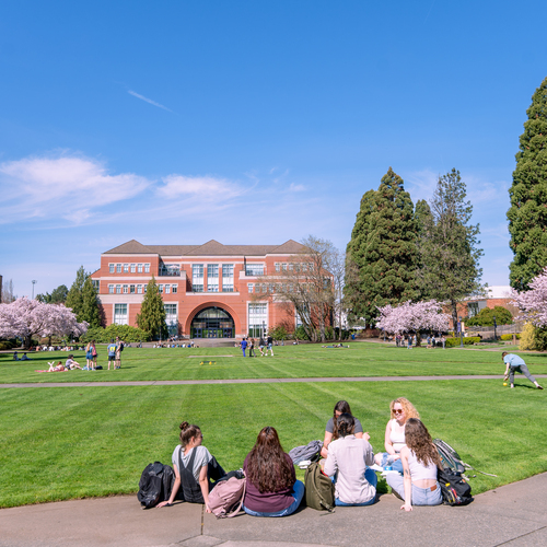 The University of Portland Academic Quad on a sunny day full of students sitting on the grass and enjoying the sunshine