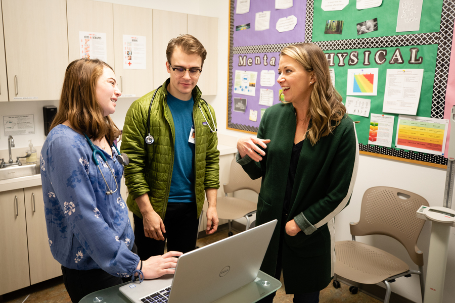 Two University of Portland nursing students in a clinic exam room at the Blanchet House where they were providing medical care to unhoused and at-risk people, speaking to a social worker