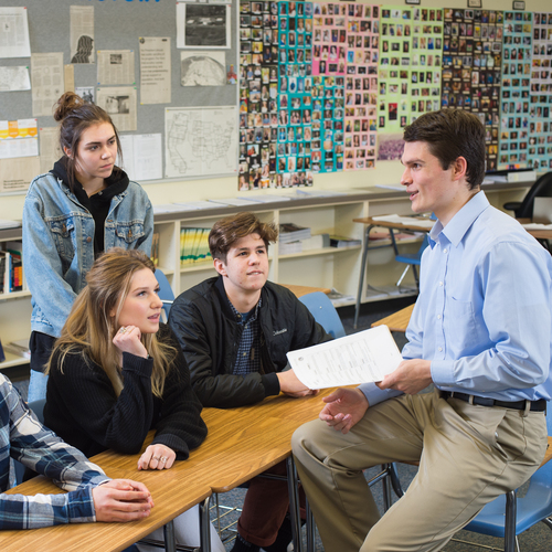 A secondary education student teacher from the University of Portland converse with high school students in the classroom during a teaching internship.