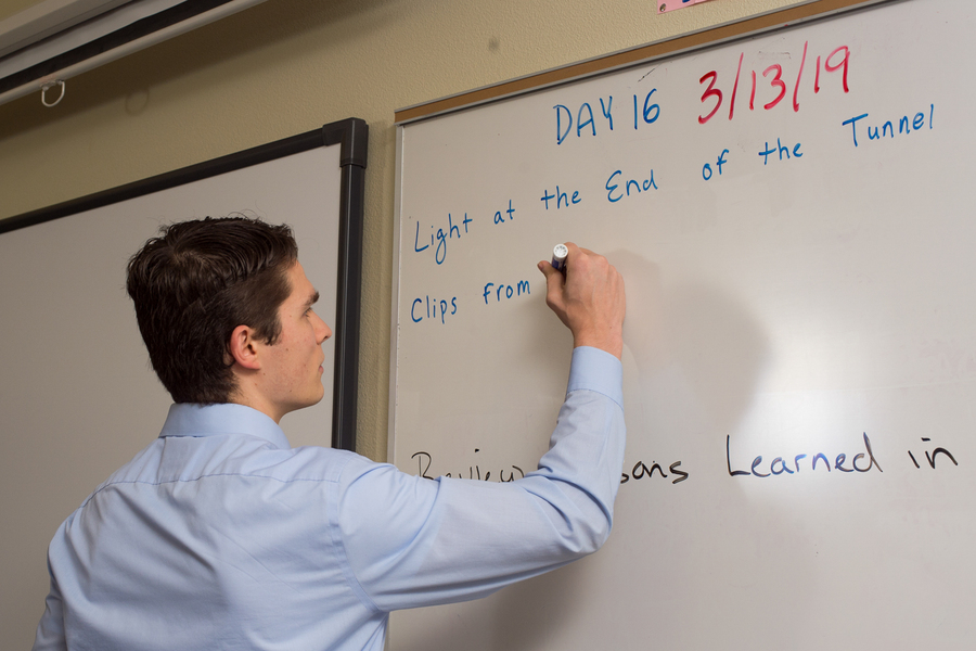 A University of Portland secondary education program student writes on a whiteboard while teaching during a high school internship program.