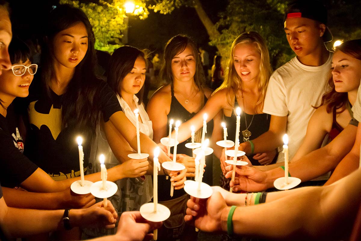 University of Portland students in a group at a candlelight celebration for the bell tower bring their lit candles together in a circle