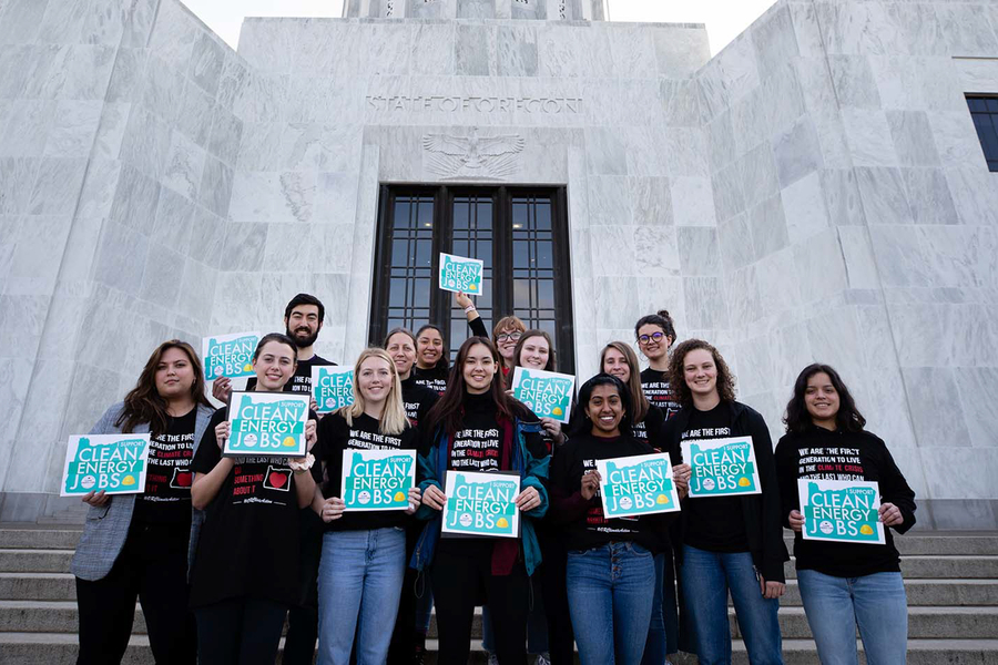 A group of environmental ethics students from the University of Portland pose with signs on the steps of the Oregon state capitol building.