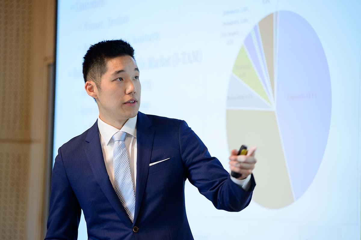 University of Portland business student in a suit and tie presenting before a pie chart at the Innovation 100K Competition