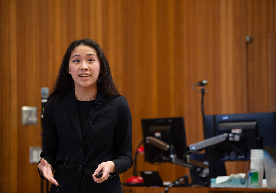 An organizational communication student stands in front of a classroom lectern while giving a presentation on Founders Day at the University of Portland.