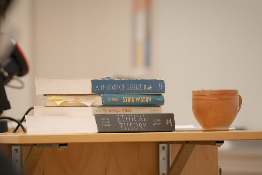 A close-up image of stack of philosophy books and a ceramic mug on the lectern during a class at the University of Portland.