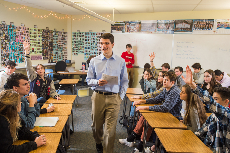 A secondary education student from the University of Portland stands in the midst of a local high school classroom while teaching during an internship.