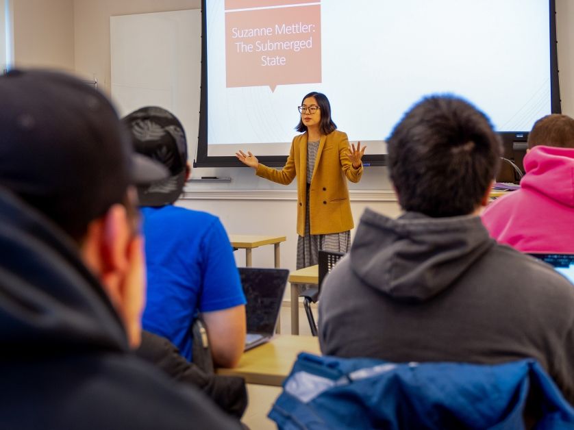 A professor delivers a lecture to students in a large classroom.