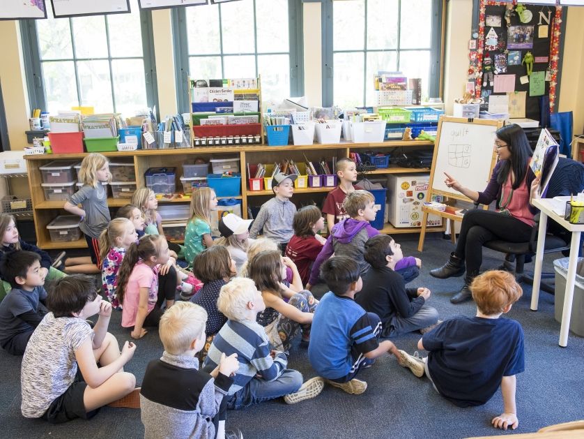 A teacher reads to a group of elementary students in a school classroom.