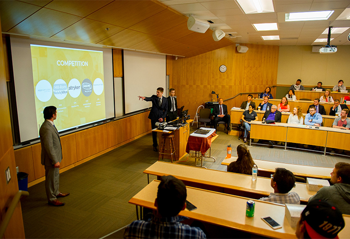 Student presenting business plan in front of judges in a tiered classroom in Shiley Hall